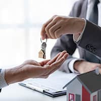 Person handing over keys to a home after signing a contract